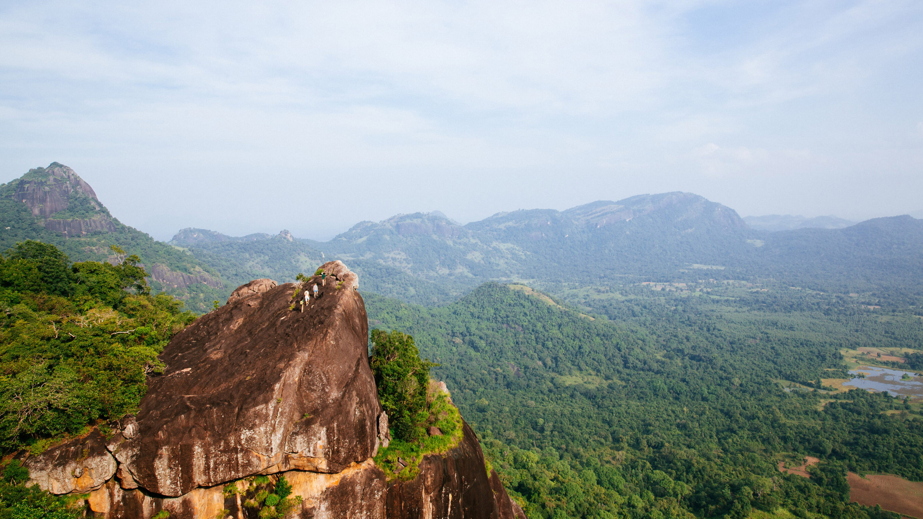 The ancient rock fortress of Sigiriya as seen from afar with foliage-cloaked mountains in the backdrop in Sri Lanka.