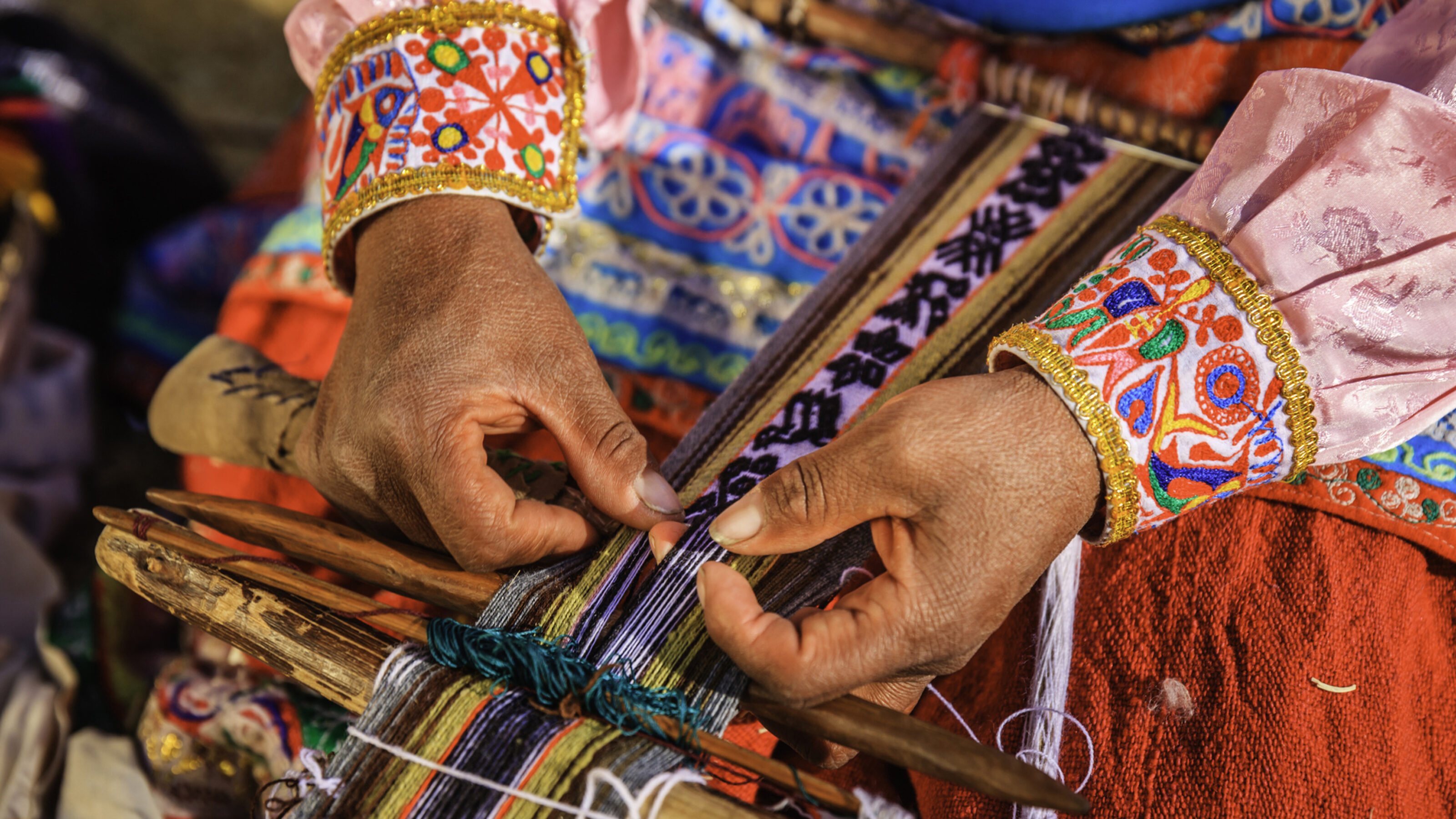 A woman's hand weaving traditional, colourful wool fabric in Peru
