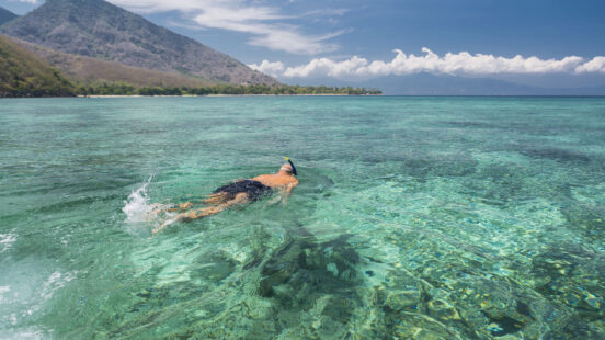 Man snorkeling in crystal blue waters, Komodo Islands, Indonesia