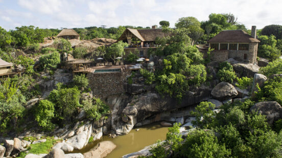 View of Legendary Mwiba Lodge set upon the rocks among the trees above the river, Mwiba Wildlife Reserve Tanzania