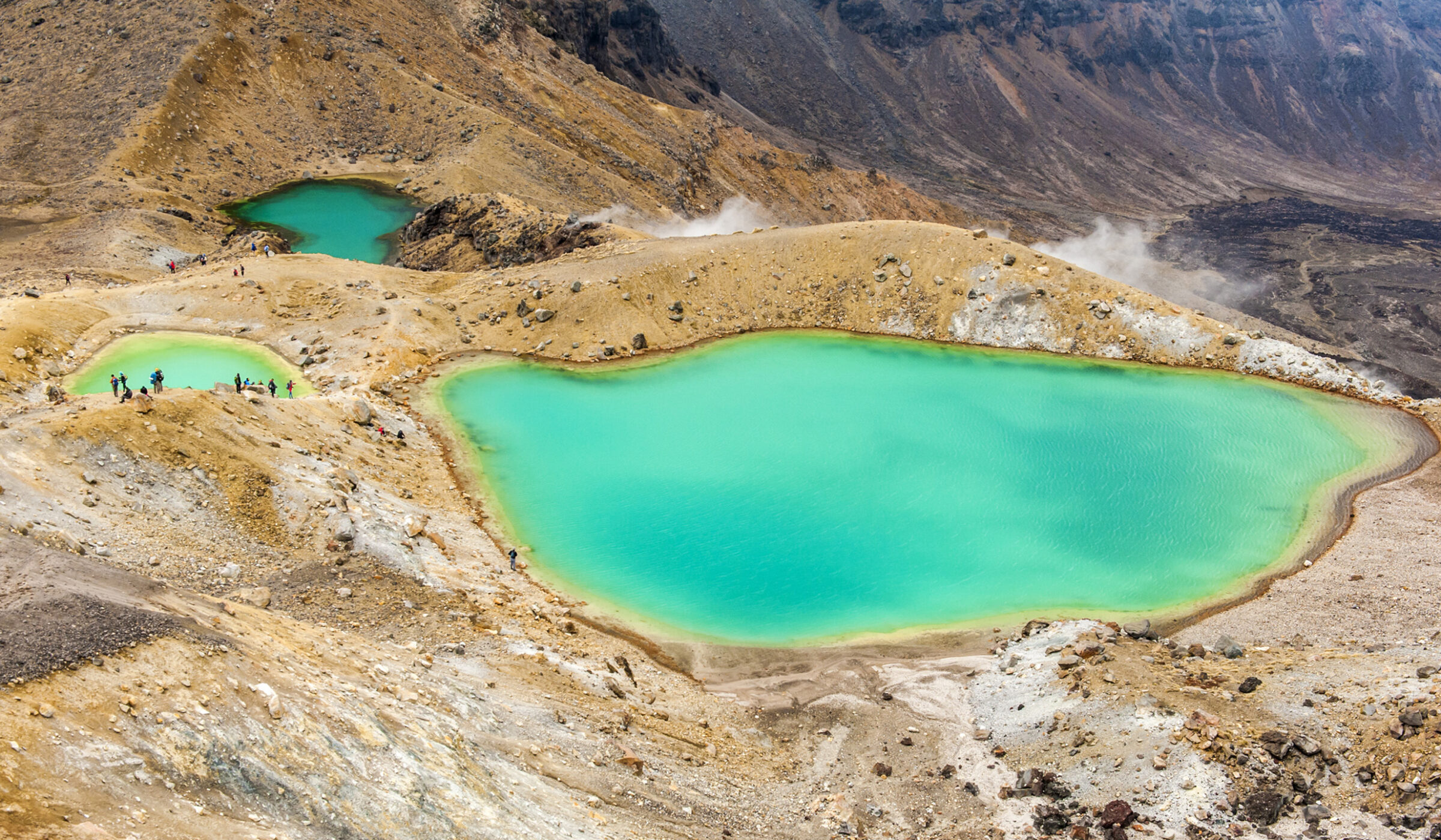 Three vibrant turquoise volcanic lakes surrounded by rocky, barren terrain.