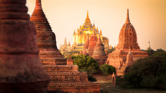 Close-up of ancient red brick pagodas and stupas in Bagan illuminated by the warm light of sunset.