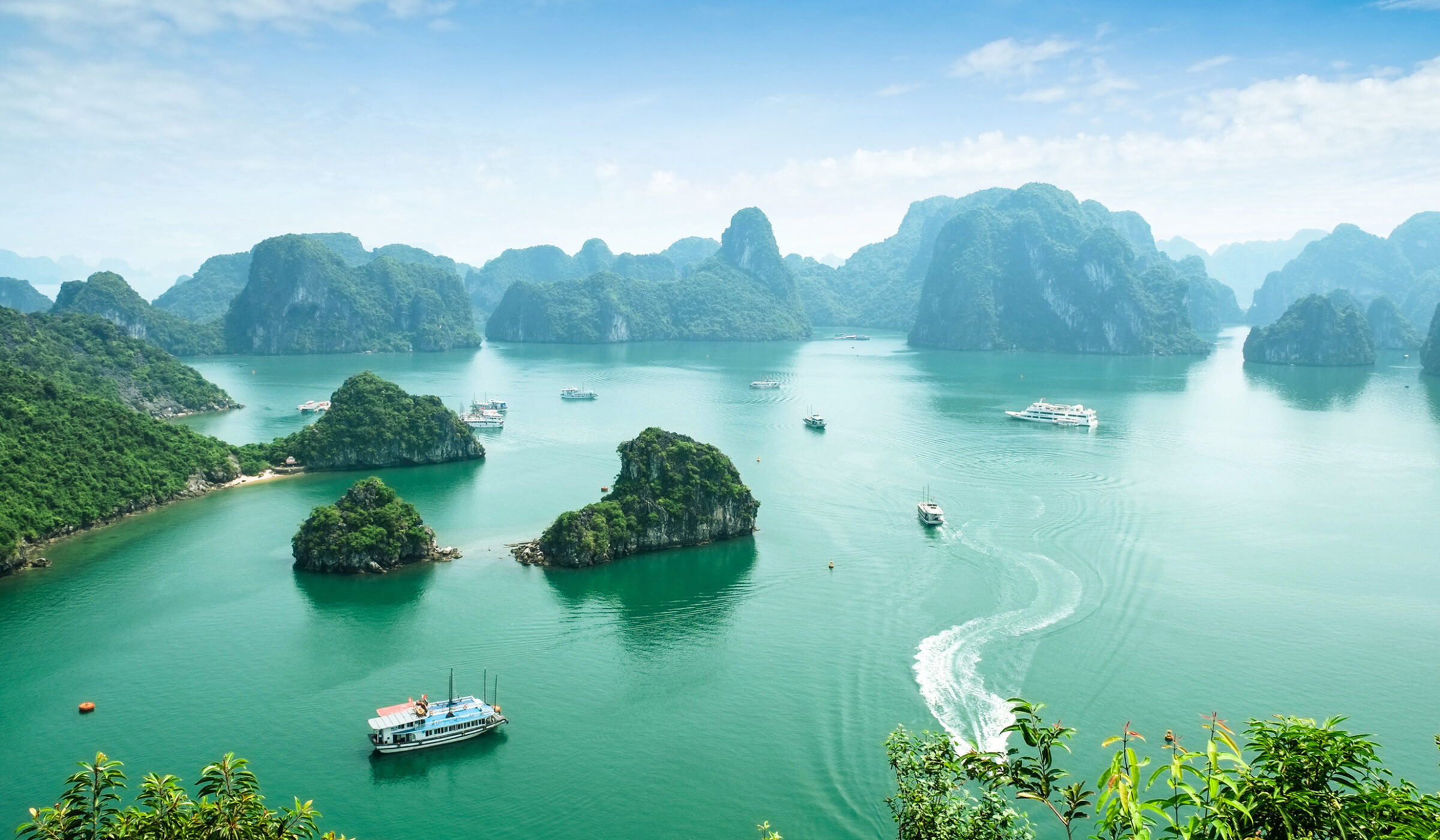 High-angle view of green limestone karsts and islands scattered across the turquoise waters of Ha Long Bay, Vietnam.
