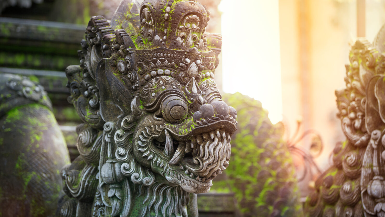 Close-up of a mossy stone dragon statue, a cultural site on luxury Bali holidays.