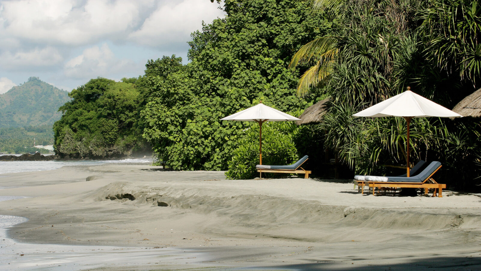 Beach chairs and umbrellas on a tropical shore, ideal for luxury Bali vacations.