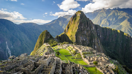 Panoramic view of the ancient Incan citadel of Machu Picchu and surrounding green mountains.