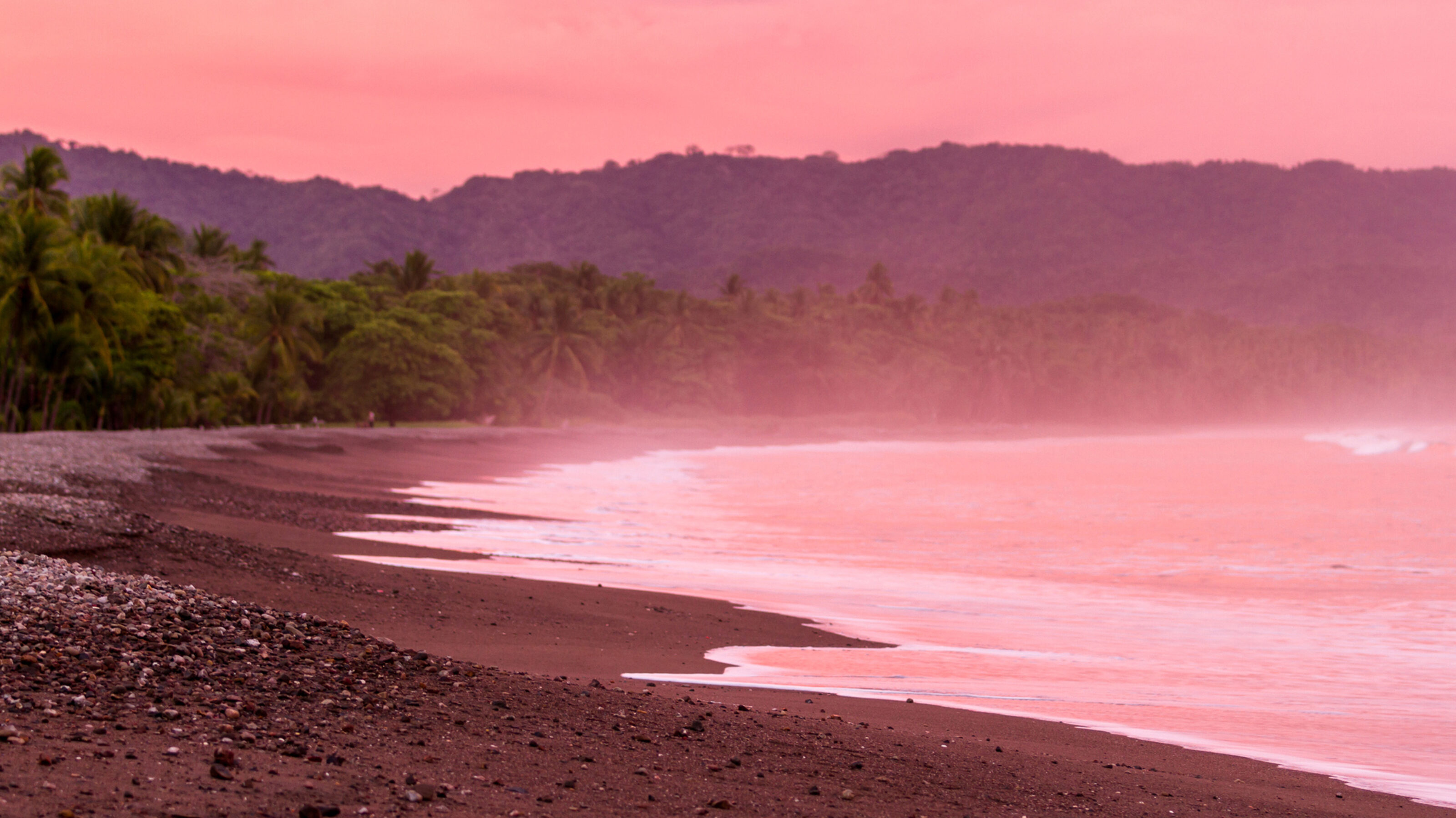 Beautiful sunset on a beach in Costa Rica with amazing vivd color in the clouds and also reflecting on the sand and water