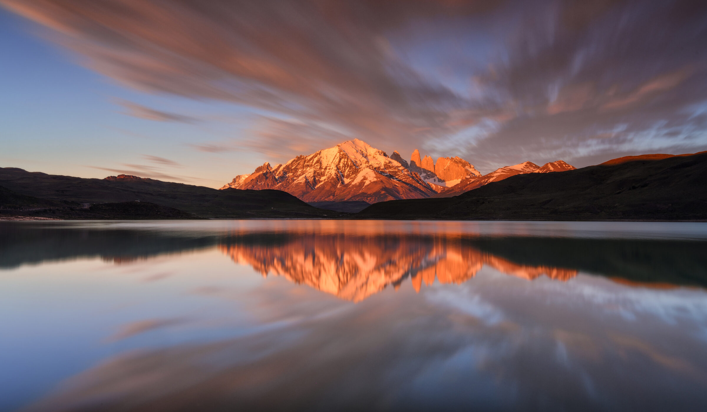 A mountain range and its reflection in a still lake at sunset on luxury Chile trips.