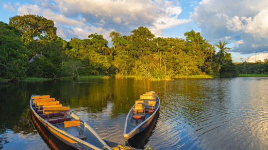 Two traditional wooden canoes at sunset in the Amazon River Basin with the tropical rainforest in the background inside the Yasuni National Park, Ecuador, South America.