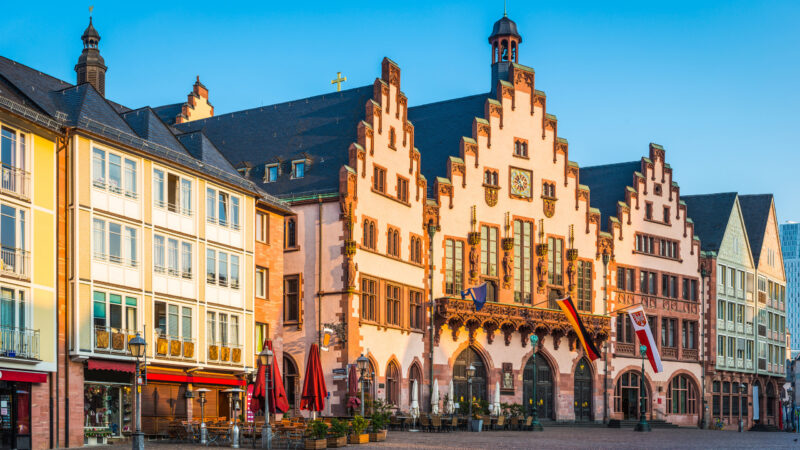 Warm light of daybreak illuminating the medieval facade of Romer City Hall overlooking the plaza of Romerberg in the historic Alstadt district of Frankfurt am Main, Germany.