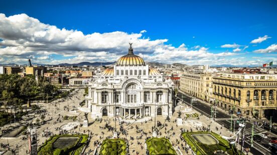 High-angle view of the ornate Palacio de Bellas Artes building in a city plaza with people walking below.