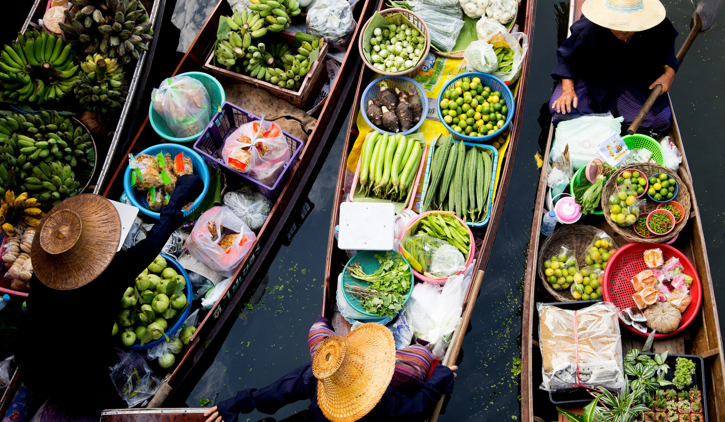Aerial view of several boats filled with fresh produce at a traditional floating market. luxury food and wine trips.