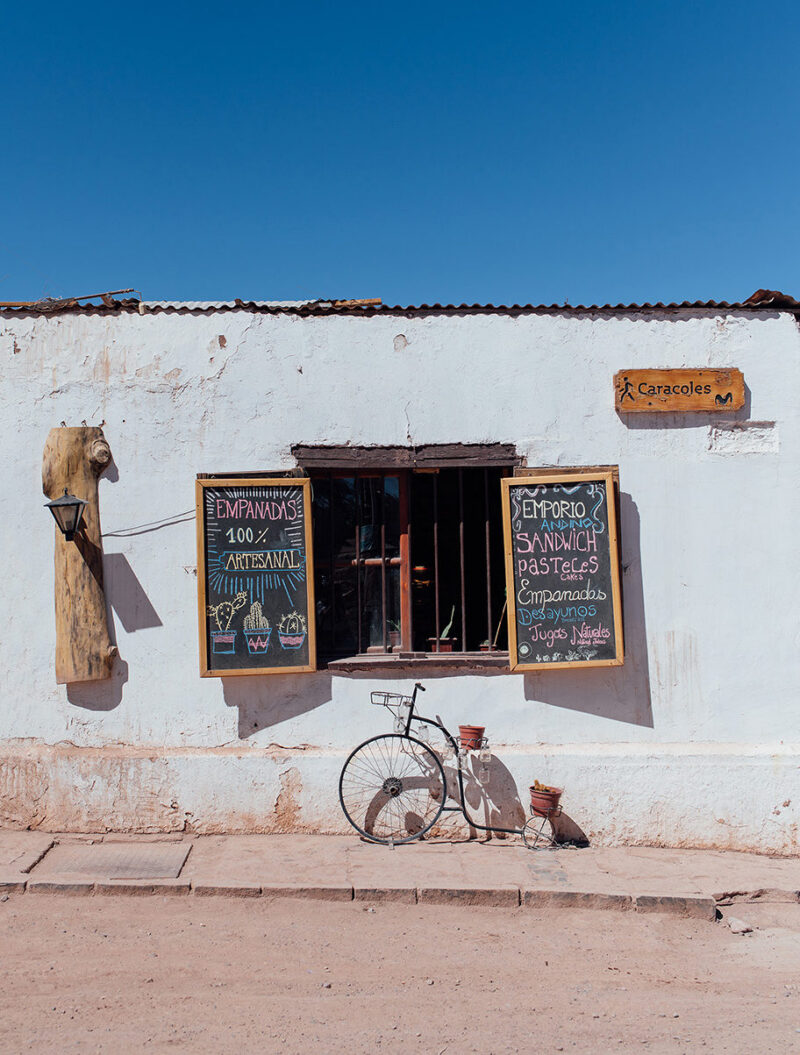 A white building with chalkboard menus and a decorative bicycle, ideal for luxury Chile tours.