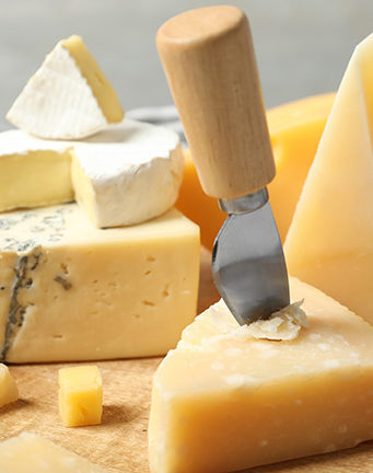A variety of artisanal cheeses on a wooden board for luxury France vacations.