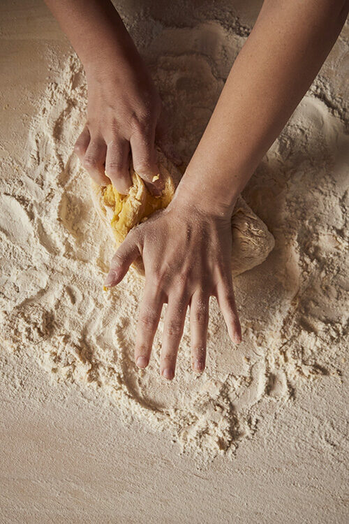 Luxury Italy Tours - A shot of two hands making fresh dough, kneading the dough on a flour-covered surface