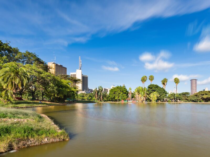 Luxury Kenya Safari Tours - A city park featuring a large pond in the foreground with green trees and skyscrapers in the background.