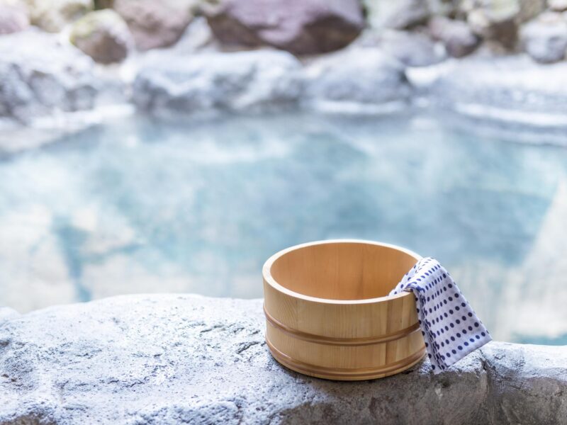 Private Japan Luxury Tours- Japanese hot spring, open-air bath with wooden pot and blue and white spotted towel on the edge