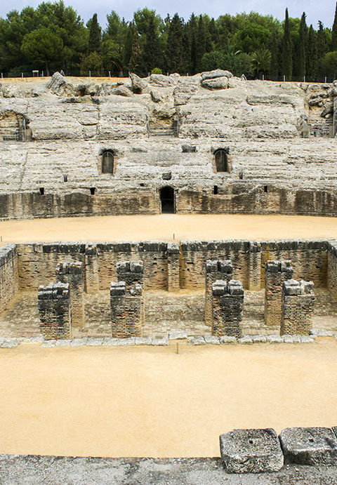 Preserved ruins of a Roman amphitheater with lower-level brick structures and stone seating, ideal for luxury Spain vacations.