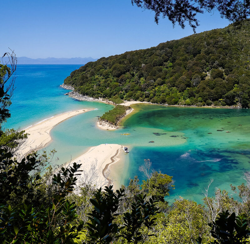 Aerial view of a turquoise lagoon and golden sand beaches during luxury New Zealand tours.
