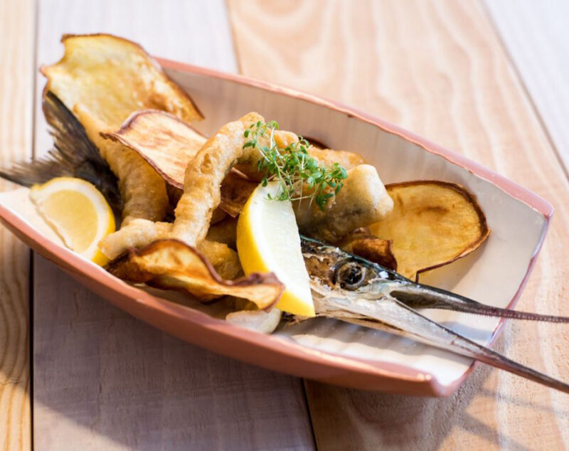 Close-up of a plated fried fish dish with chips and lemon wedges, representing a culinary stop on luxury Portugal vacations.