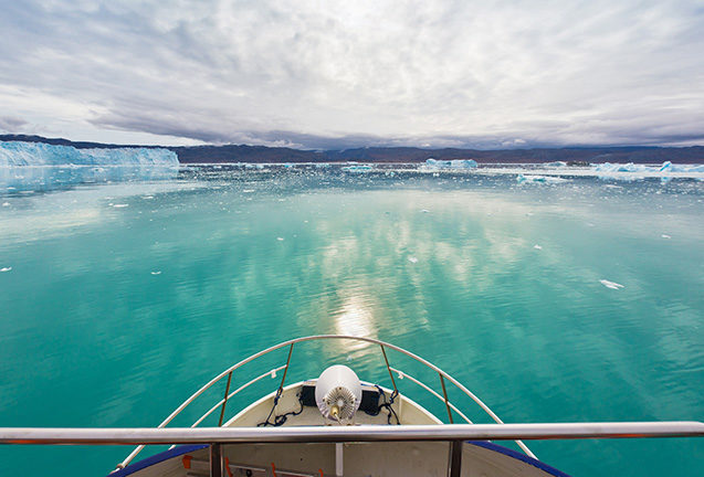 View from a boat bow of turquoise water and distant glaciers on luxury Polar trips.
