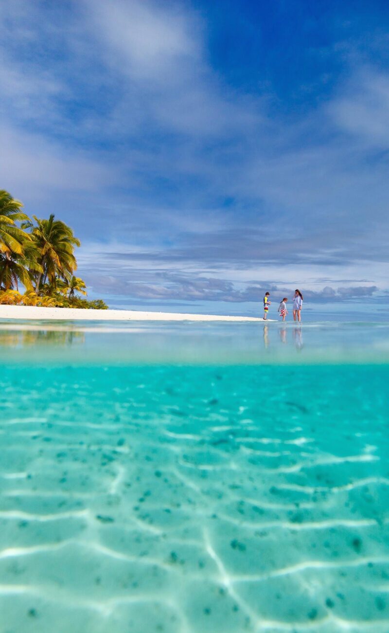 Split-view image of people on a tropical beach and clear blue water for luxury Australasia trips.
