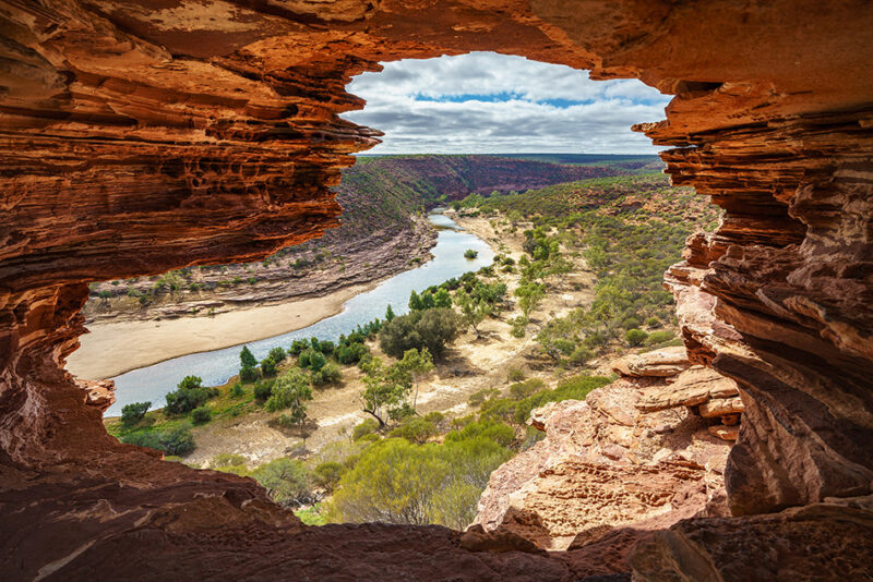 View of a river through a natural rock window formation during luxury Australasia holidays.
