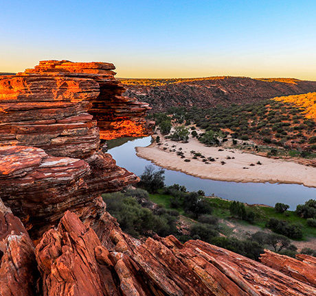 Dramatic red rock canyon cliffs overlooking a serene river during luxury Australasia vacations.