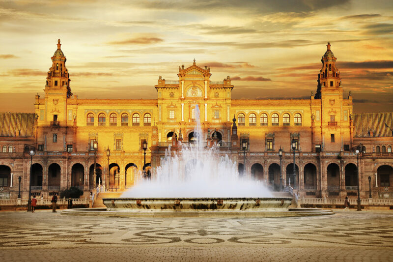 The central fountain illuminated at dusk in front of the Plaza de España, Seville.