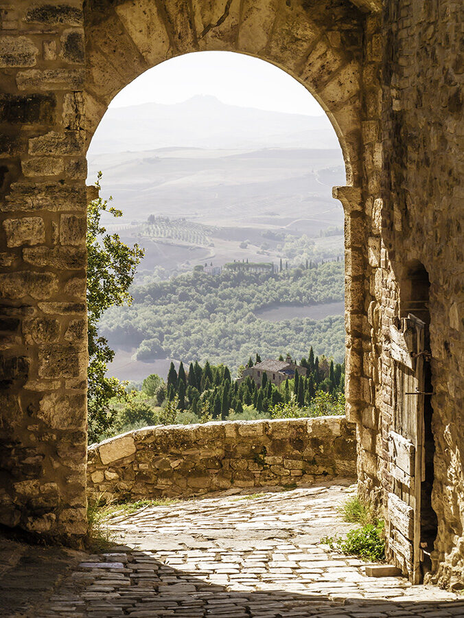 A stone archway framing a scenic view of the Tuscan landscape, perfect for luxury Tuscany vacations.