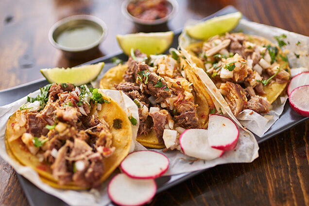 Three meat tacos with cilantro and radish on a plate during luxury Latin America honeymoon trips.