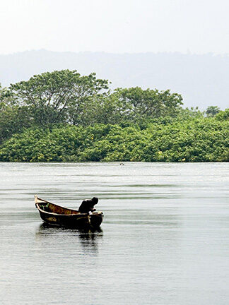 A person in a small boat on a quiet lake during luxury Africa honeymoon vacations.