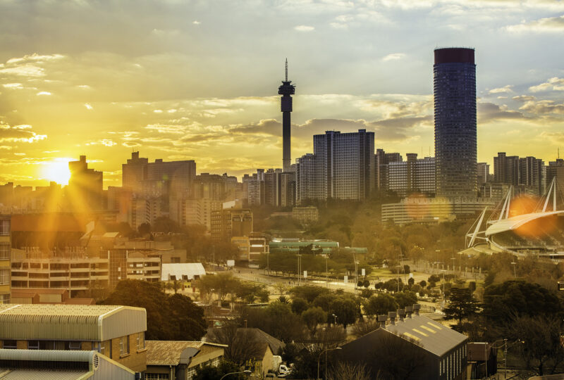 Golden sunset over a city skyline with a tall communications tower for luxury Africa honeymoon tours.