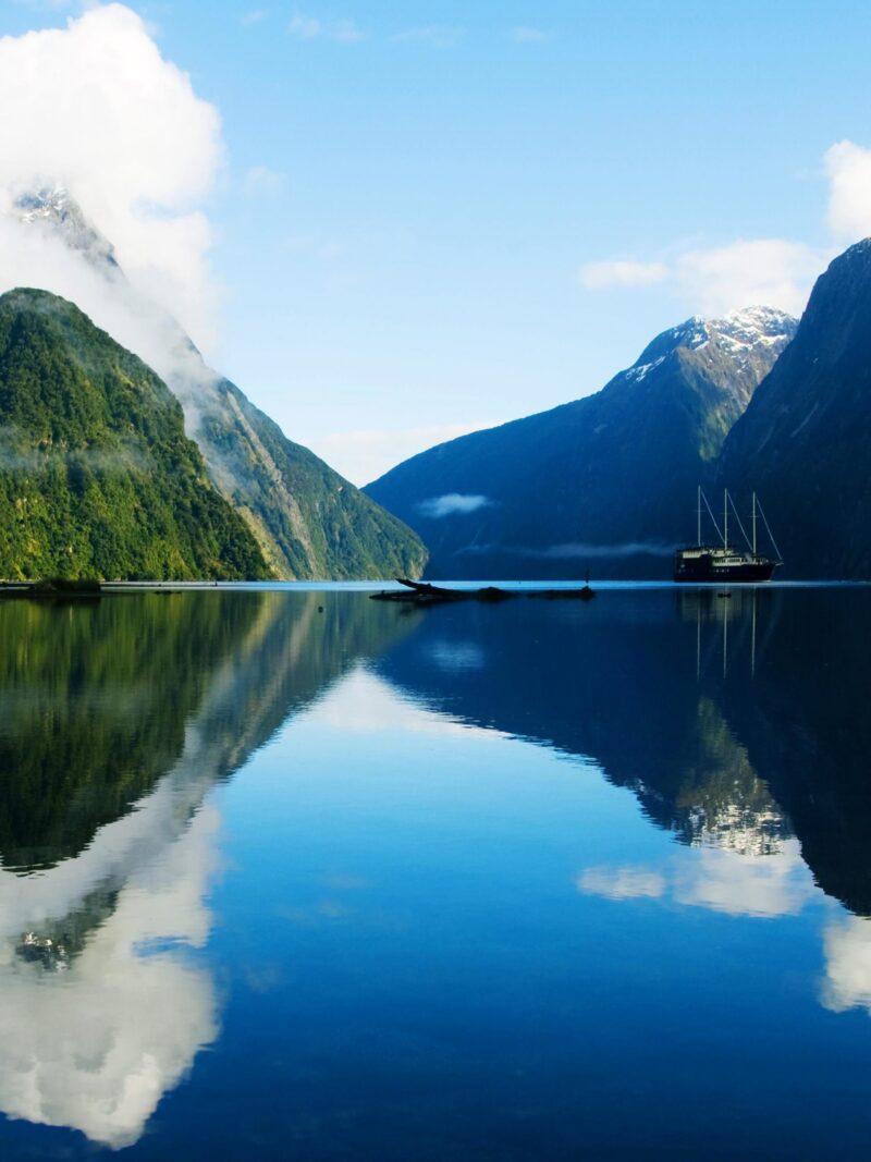 Ship on a calm fjord with mountain reflections during luxury grand tours and safaris.