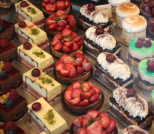 A display of assorted gourmet pastries, including strawberry tarts and cream-topped slices. luxury food and wine trips