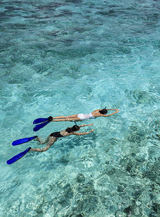 Two people snorkeling in clear turquoise ocean water on luxury Indian Subcontinent tours.