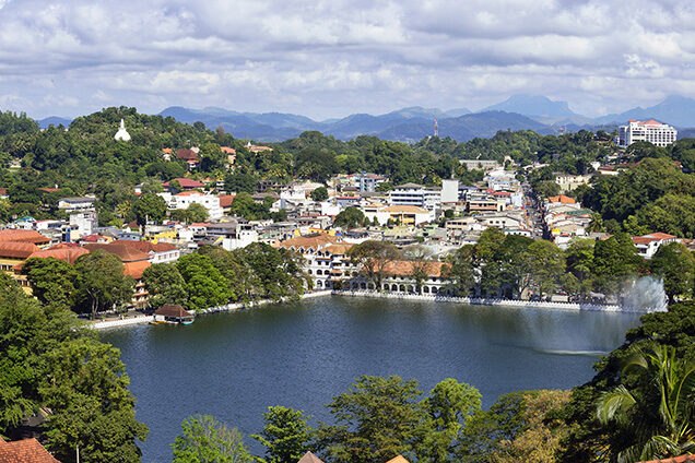 Aerial view of a city lake surrounded by white buildings and green hills on luxury Indian Subcontinent tours.