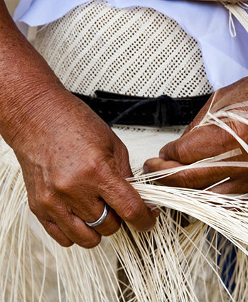 Close up of hands weaving a straw hat during luxury culture tours.