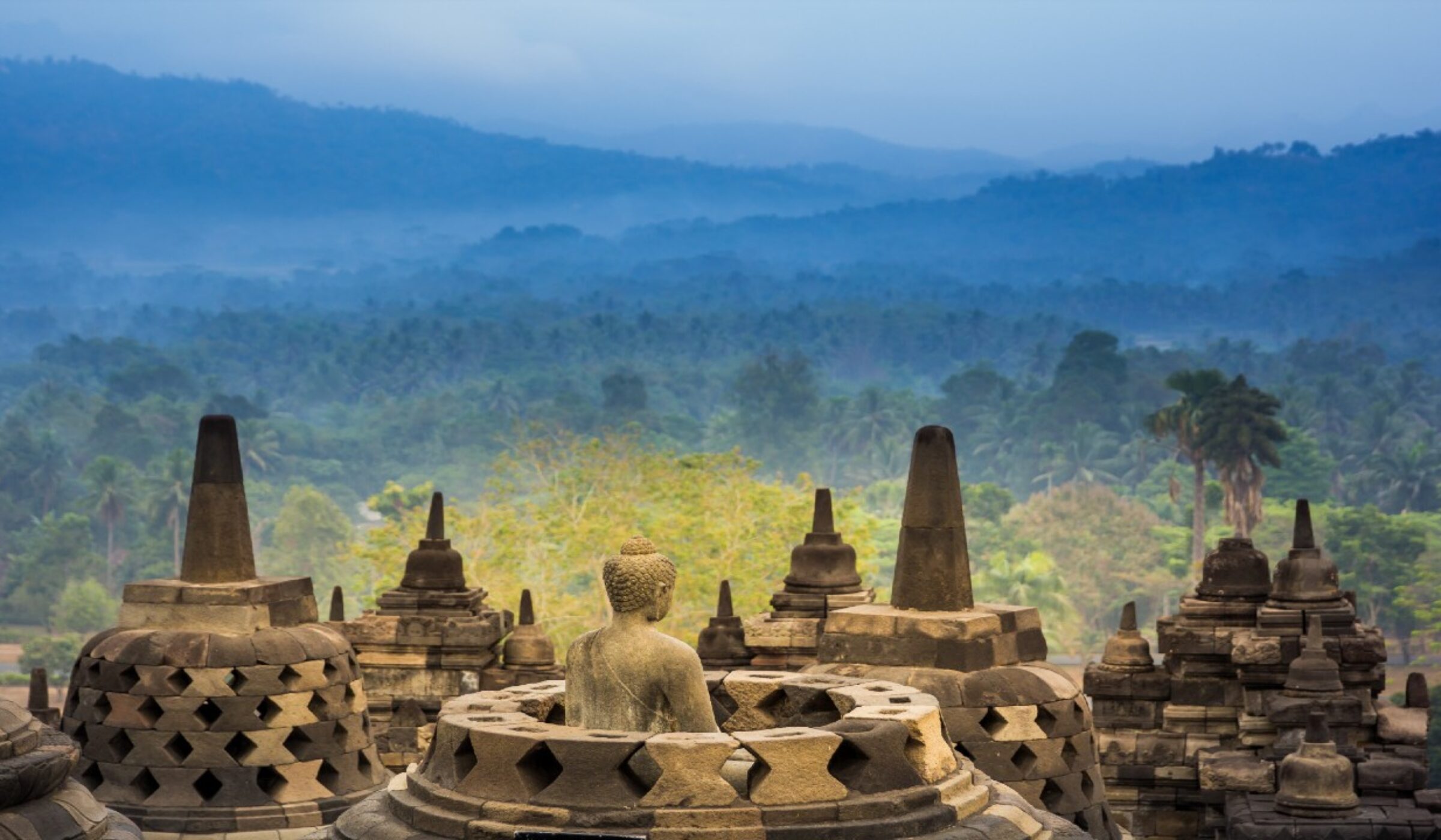 Openwork stupas of Borobudur Temple against a backdrop of lush jungle on a luxury Asia tour