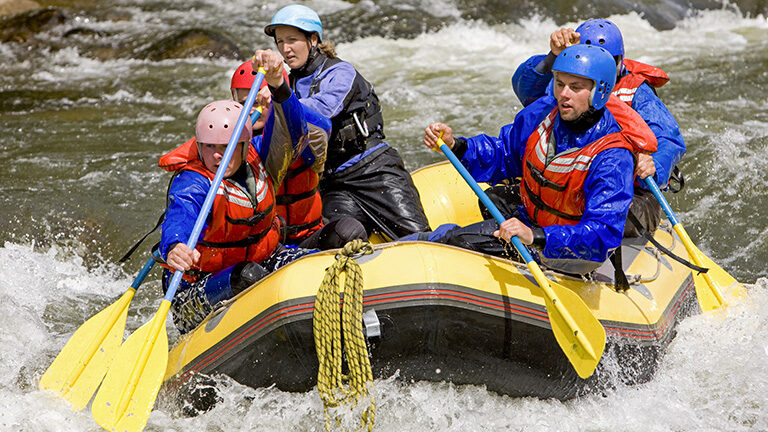 A group of people navigate river rapids in a yellow raft during luxury Latin America family holidays.