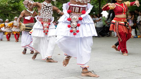 Traditional Kandyan dancers in white and red costumes perform in a public procession.
