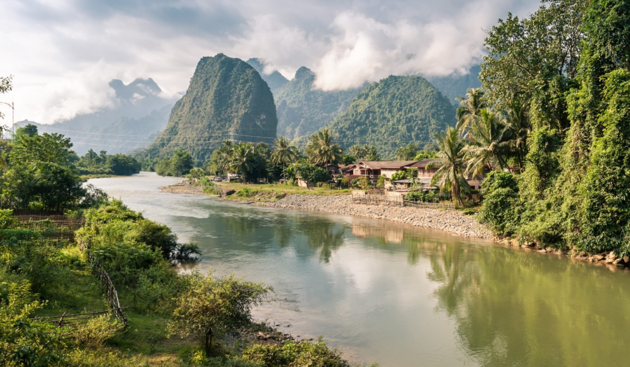 A peaceful river winding through green mountains and karst formations on luxury Laos holidays.