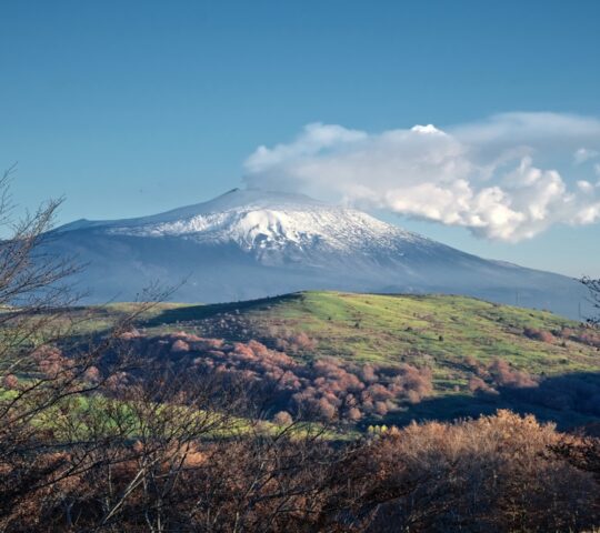 Mount Etna smoulders in the distance