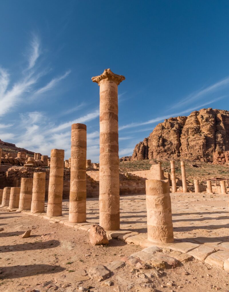 Sandstone columns of the Great Temple rise against clear blue skies in Petra, Jordan.