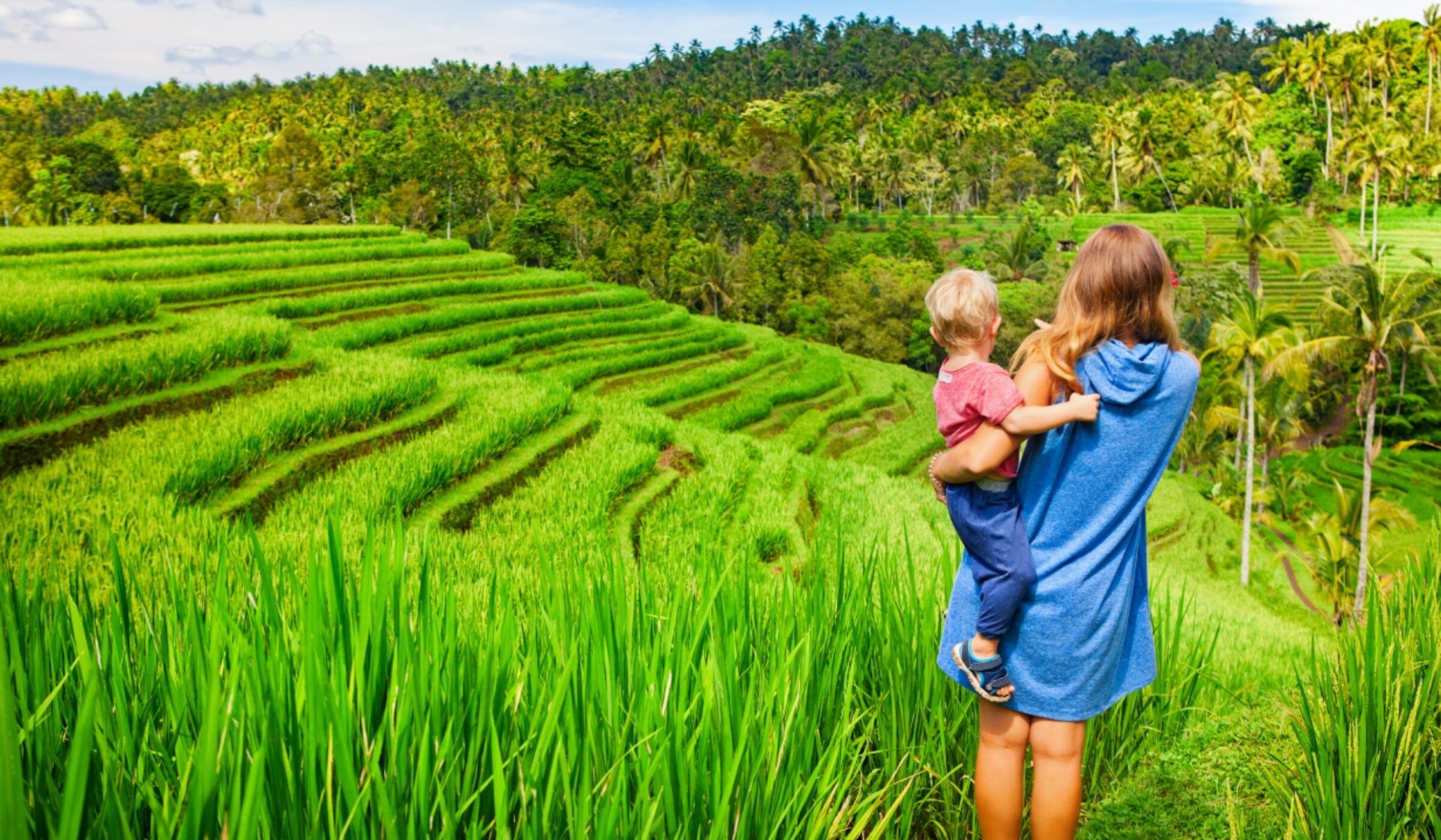 A woman and child overlooking lush green rice terraces during luxury asian family tours.