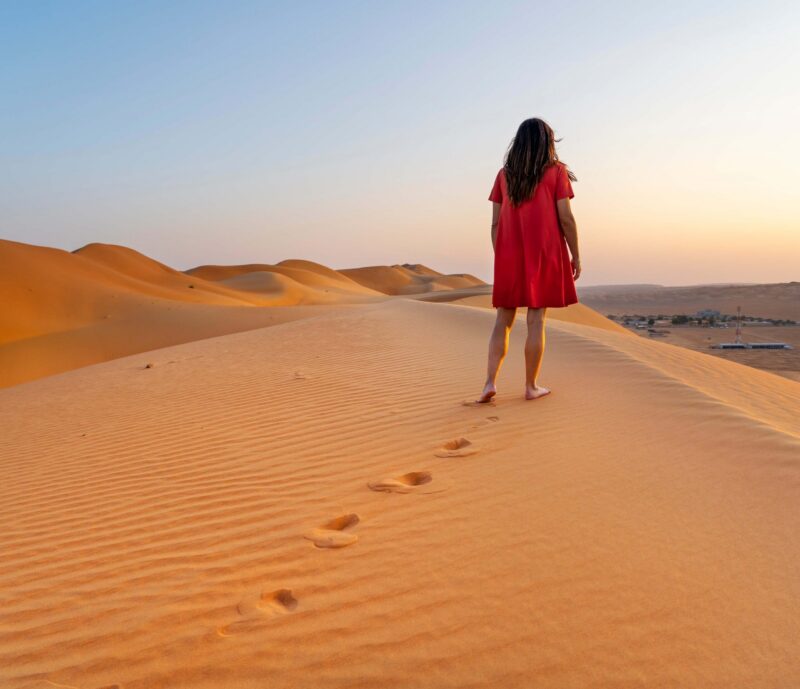A person in red standing on a sand dune
