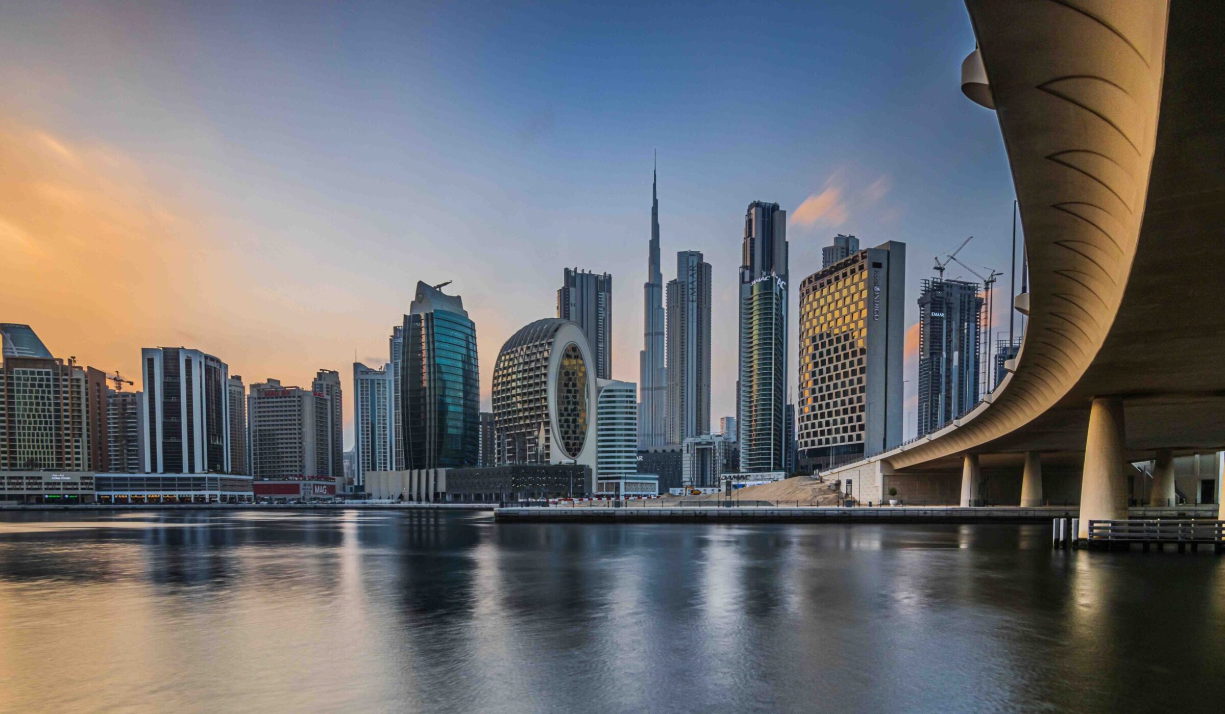 Dubai skyline at sunset featuring the Burj Khalifa and a curved bridge for luxury United Arab Emirates tours.
