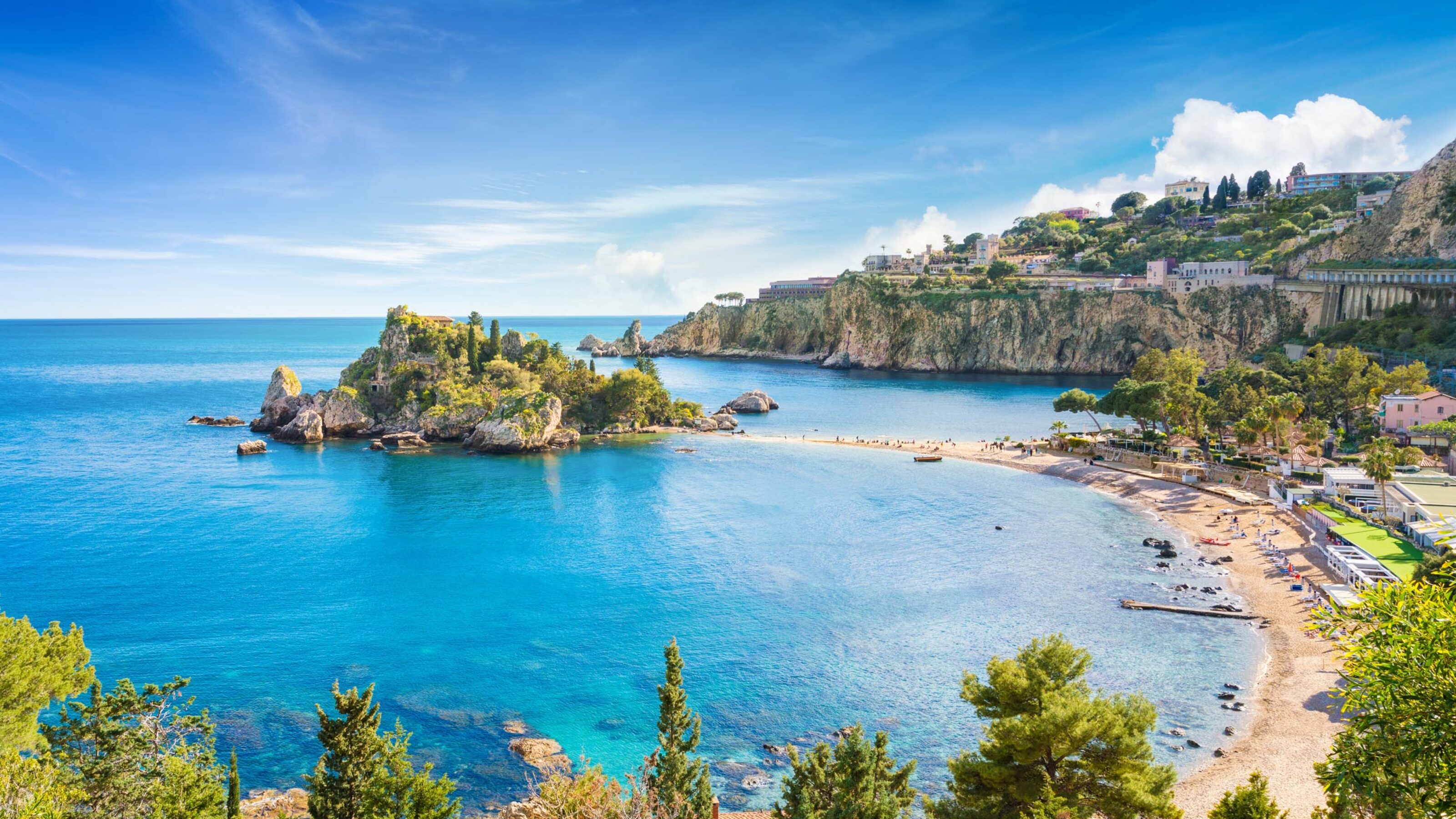 Aerial view of the Isola Bella island and beach in Taormina, Sicily, under a bright blue sky.
