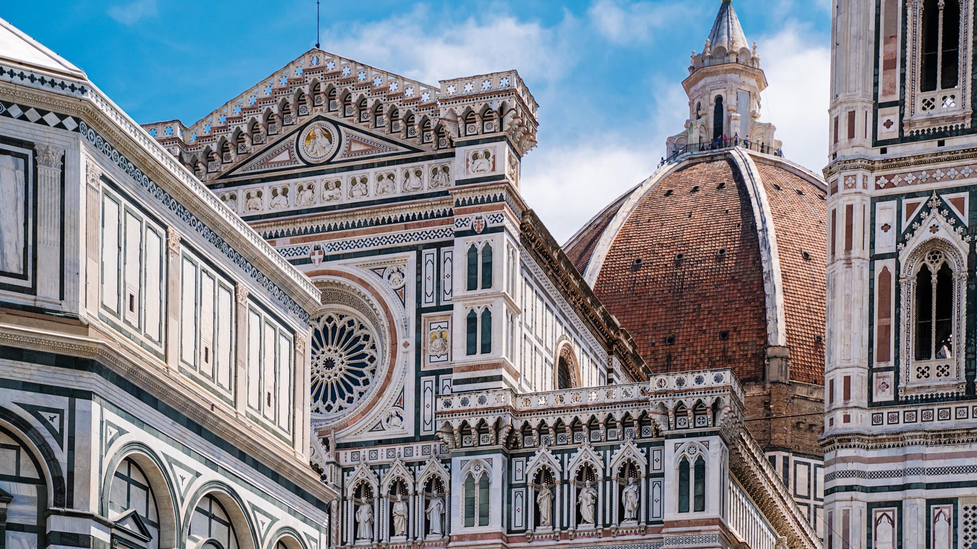 Detailed view of the marble facade and large red brick dome of the Florence Cathedral in Italy.