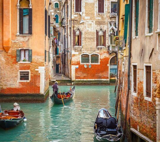 A gondolo meanders down a canal in Venice